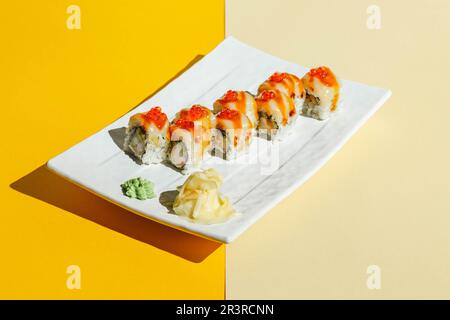 Involtini di sushi con anguilla, gamberi, cetrioli e formaggio cremoso, decorati con caviale rosso. Luce dura, ombra profonda Foto Stock