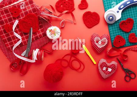 Vista dall'alto dei materiali per cucire e lavorare a maglia. San Valentino regali fatti a mano sfondo Foto Stock