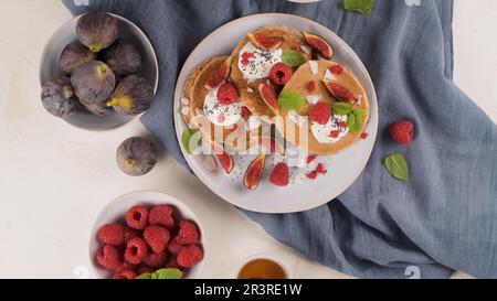 Sana colazione estiva, frittelle classiche americane fatte in casa con frutti di bosco freschi, yogurt e miele, mattinata sfondo di pietra chiara. Foto Stock