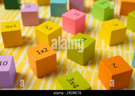 Cubi colorati con numeri e moltiplicazioni su sfondo giallo Foto Stock