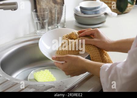 Piastra di pulizia donna con asciugamano in cucina, primo piano Foto Stock