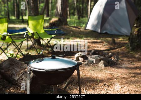 Cucinare in un campeggio su un fuoco aperto in un calderone. Picnic all'aperto, vacanze estive, accessori da viaggio Foto Stock