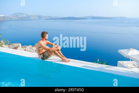 Giovane uomo che si rilassa in piscina durante le vacanze a Santorini Infinity con vista sull'oceano Foto Stock