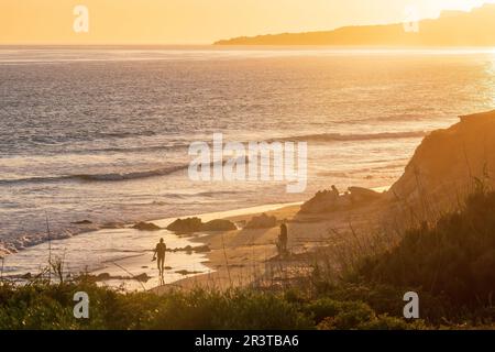 La gente cammina lungo la spiaggia al tramonto a Playa de los Lances sullo stretto di Gibilterra, Tarifa, Spagna Foto Stock