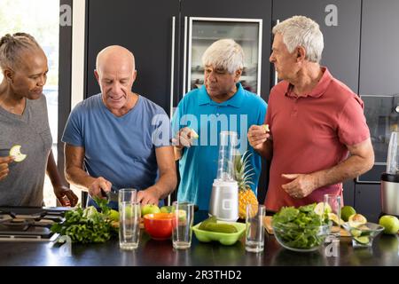 Felice diversi amici anziani discutere gli ingredienti per la preparazione di frullati sani in cucina Foto Stock