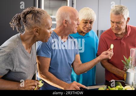 Felice diversi amici anziani discutere gli ingredienti per la preparazione di frullati sani in cucina Foto Stock