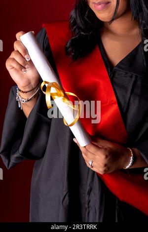 Studentessa in una foto di laurea. Fine del corso di laurea con diploma di laurea. Università, tunica con cappello Foto Stock