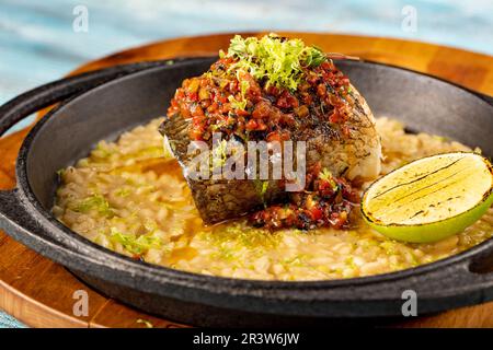 Un pezzo di pesce con salsa su un letto di riso o orzo, grigliato con lime. Piatti originali dello chef del ristorante Foto Stock