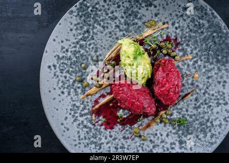 Tartaro gourmet in stile moderno crudo di filetto di manzo chianina con avocado e capperi in amareno e salsa al tartufo servito come t Foto Stock