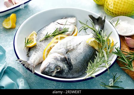 Pesce fresco del dorado crudo con limone e rosmarino. Orata di mare, dorado. Frutti di mare, cibo sano Foto Stock