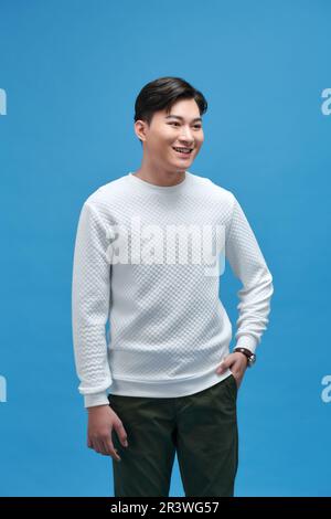 Elegante e attraente giovane uomo sorridente che indossa una t-shirt bianca in posa in studio Foto Stock