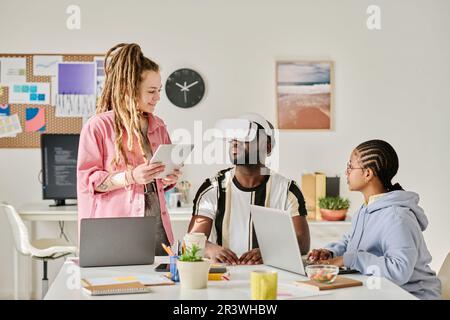 Team di programmatori che testano gli occhiali per la realtà virtuale durante le riunioni in ufficio IT Foto Stock