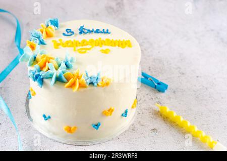 Torta bento alla moda con un'iscrizione blu-gialla in ucraino "buon compleanno" su sfondo chiaro. Torta di compleanno, torta Bento per due Ukrai Foto Stock