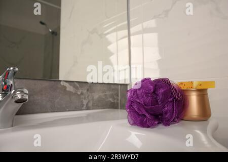 Soffio doccia viola e prodotti cosmetici sul lavandino in bagno, spazio per il testo Foto Stock