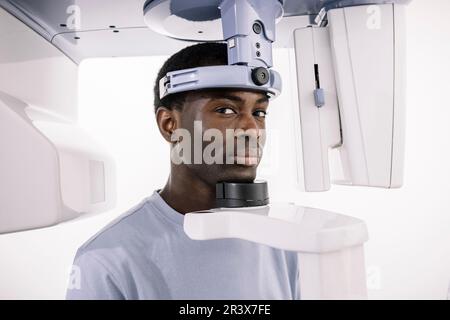 Ritratto dell'uomo afroamericano seduto ad una macchina a raggi X nell'ufficio di un dentista Foto Stock