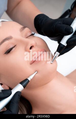 Cosmetologia. Bella donna a Spa Clinic ricevere stimolante trattamento viso elettrico dal terapista. Primo piano della giovane FEMA Foto Stock