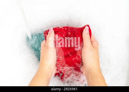 Donna lavaggio mani camicia rosso brillante Foto Stock