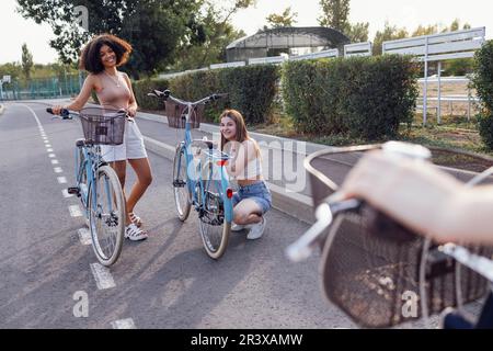 Adolescenti di diverse nazionalità e aspetto in bicicletta percorrono una strada cittadina Foto Stock