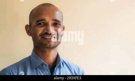 Felice uomo indiano che indossa una camicia blu e sorridente. Foto Stock