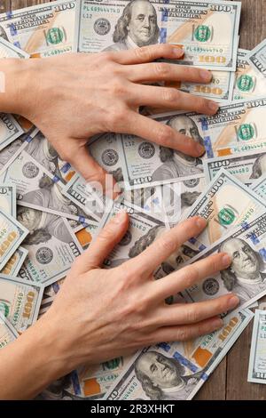Mani avide coperte e premi banconote di 100 dollari. Il concetto di avidità, corruzione, corruzione, stinginess, affari, profitto, accumulazione. Foto Stock