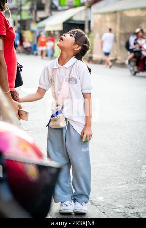 Una giovane ragazza tailandese attende un giro a casa dopo la scuola nella città di Pattaya Thailandia. Foto Stock