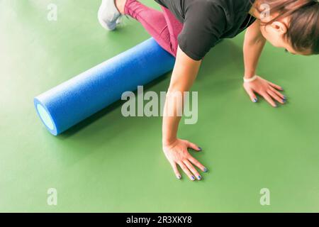 Femmina attraente facendo schiuma esercizio del rullo e che pongono nel moderno centro fitness Foto Stock