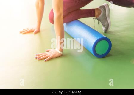 Femmina attraente facendo schiuma esercizio del rullo e che pongono nel moderno centro fitness Foto Stock