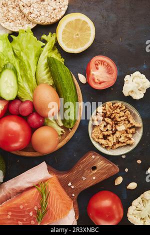 Ketogenic, Paleo, FODMAP, concetto di dieta. Frutta, verdura, salmone, verdi su sfondo nero tavolo. Foto Stock