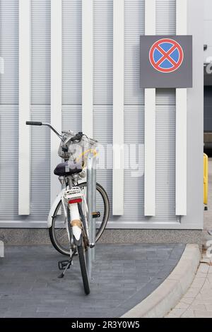 Abbiamo parcheggiato la bicicletta in un supermercato, dietro di esso c'è un cartello di divieto di sosta sul muro Foto Stock