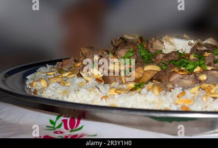 Carne di cammello con riso tradizionale arabo piatto principale ristorante pranzo servito con mandorle e semi di pino. Foto Stock