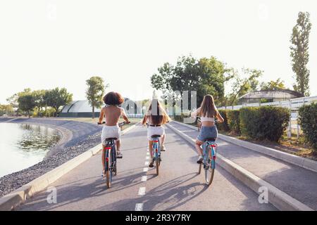 Adolescenti di diverse nazionalità e aspetto in bicicletta percorrono una strada cittadina Foto Stock