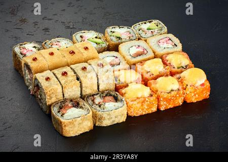 Sushi impostare sushi e rotoli unagi maki su ardesia di pietra nera su sfondo scuro. Menu Giappone Foto Stock