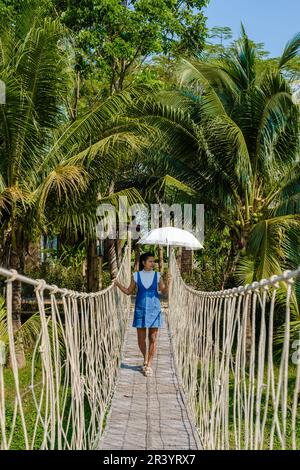 Donne asiatiche che camminano su un ponte di corda di bambù nella foresta pluviale della Thailandia Foto Stock