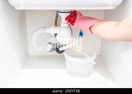 Perdita di acqua dal tubo di plastica sotto il lavandino nel locale lavanderia Foto Stock