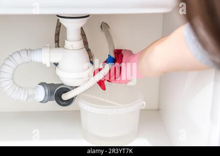 Perdita di acqua dal tubo di plastica sotto il lavandino nel locale lavanderia Foto Stock