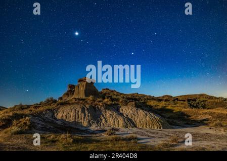 Giove e Saturno sopra le formazioni di hoodoo al Parco Provinciale Dinosaur, Alberta, Canada. Foto Stock