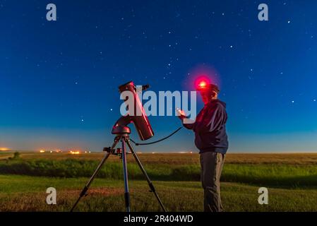 Astronomo che utilizza un telescopio Newtoniano 130mm nel cortile posteriore in una notte di luna luminosa. Foto Stock