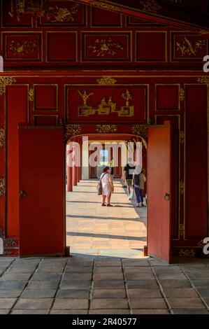 Una guida turistica e visitatori nelle lunghe gallerie del Palazzo Can Chanh nella Cittadella di Hue, città imperiale del Vietnam. Foto Stock