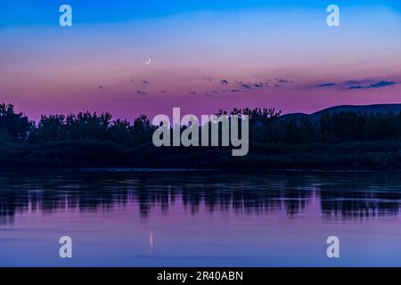 La luna crescente che si diffonda sul fiume Red Deer nel Dinosaur Provincial Park, Alberta, Canada. Foto Stock