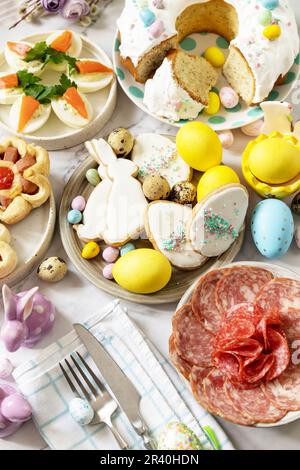 Cena festiva, brunch di Pasqua. Tavola di Pasqua scena con un assortimento di cottura, dessert, uova farcite e uova tinte su un marmo Foto Stock