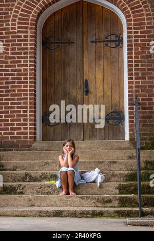 Un bambino scappato abbandonato affamato cerca cibo e riparo di fronte A Una Chiesa Foto Stock