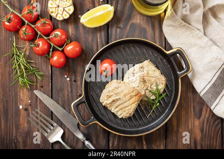 Succosa bistecca di tonno cucinata con spezie, pomodori e rosmarino su un piatto di pietra. Ristorante cibo. Frutti di mare. Stile rustico. Visualizza da Foto Stock