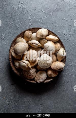 Vongole fresche crude in piatto grigio, fondo grigio Foto Stock