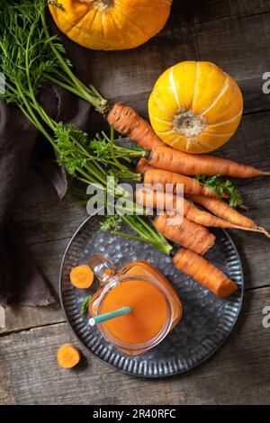 Succo fresco naturale misto, concetto di cibo sano. Vasetto di vetro di succo di carota fresco con carote fresche e zucca su una ruggine di legno Foto Stock