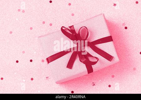 Colore trendy dell'anno 2023 - Viva Magenta. Scatola regalo di Natale fatta a mano su uno sfondo dorato. Natale presenta la scatola d'oro con r Foto Stock