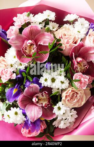 Giorno della mamma, giorno della donna o carta di compleanno. Bel bouquet di orchidee in fiore, garofani e iridi e vegetazione primaverile su un Foto Stock