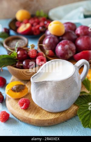 Ingredienti per un frullato sano. Latte e frutti di bosco (lampone, ciliegia, prugna, albicocca) su un piano di pietra. Mangiare sano, crudo Foto Stock
