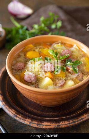 Cucina ceca: Zuppa di cavolo Zelnacka tradizionale con salsicce e verdure in una ciotola su un rustico tavolo di legno. Foto Stock