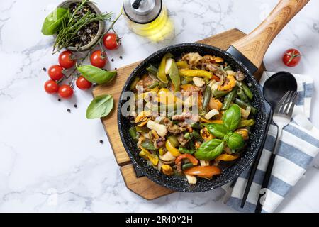 Frittura vegetariana con wok. Gamberi di pesce, calamari, seppie stufate con verdure e salsa all'aglio su un tavolo di marmo. Da a. Foto Stock