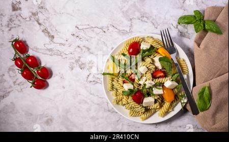 Insalata di pesto fresco con diversi colori di pomodori ciliegini e mozzarella con sfondo chiaro. Foto Stock